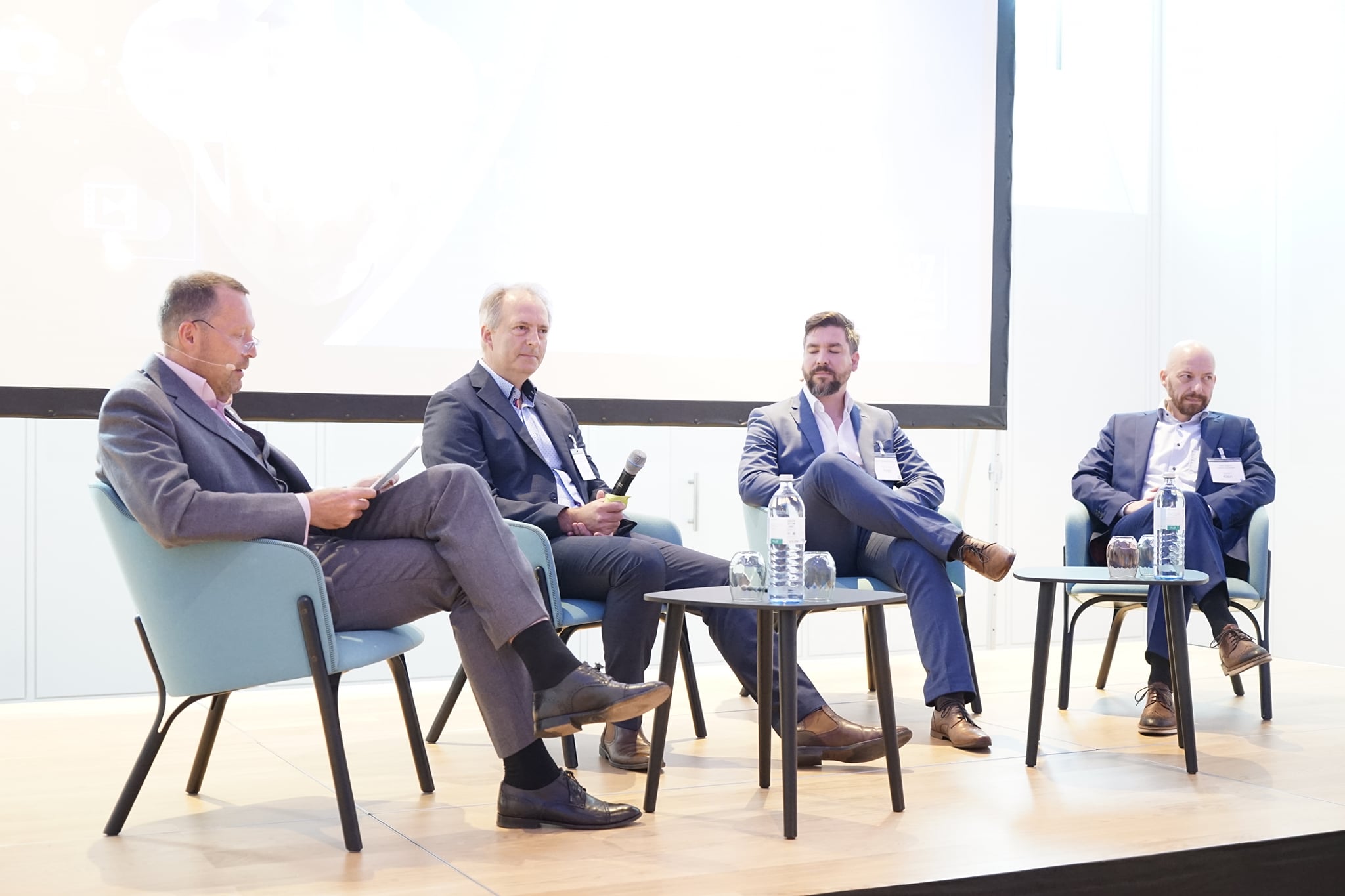 Vier Männer, sitzend, diskutieren bei einer Podiumsdiskussion