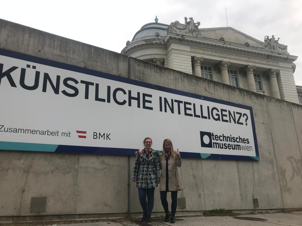 Zwei Frauen vor einem Schild mit der Aufschrift 